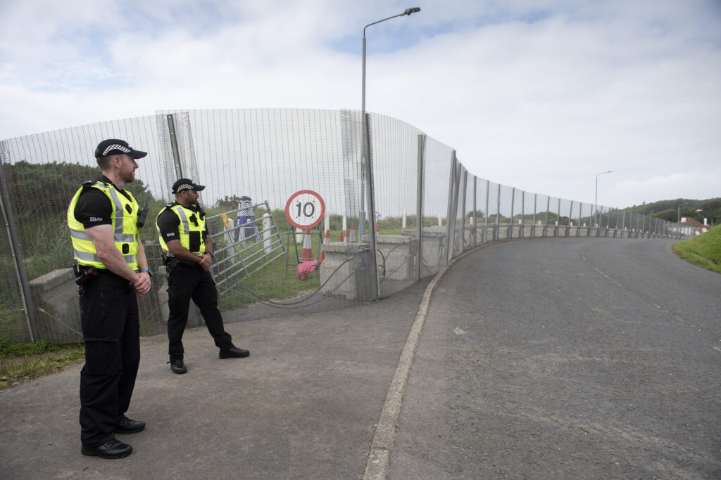 Police officers standing beside high security perimeter fencing designed to support Martyn’s Law compliance and protective security measures at a major event